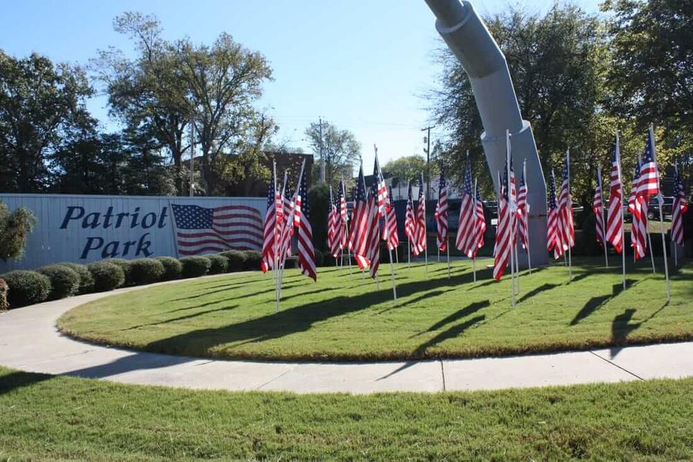 a static display of a fighter jet and several American flags and a sign that says patriot park