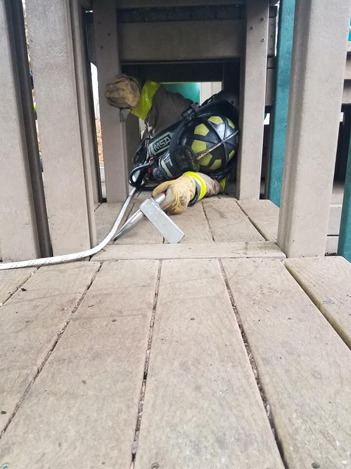 covington fire department member in full gear crawling through a tight space of a house