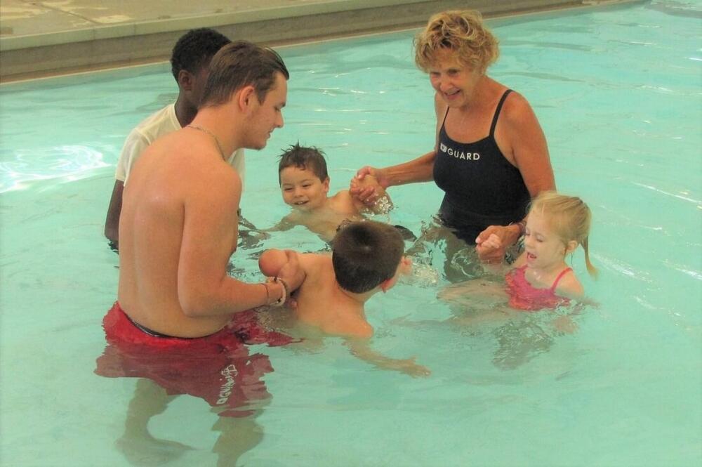 4 adults giving 3 young children swimming lessons
